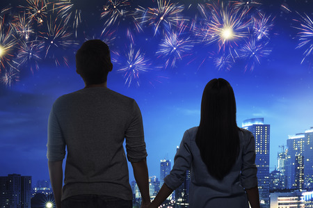 Romantic asian couple watch the fireworks together on the city at nightの写真素材