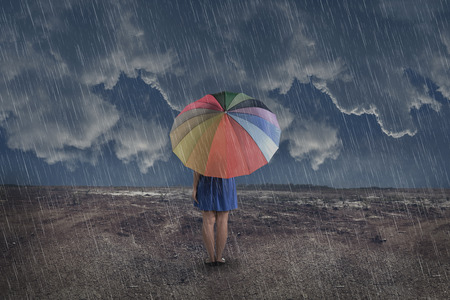 Rear view of asian woman with umbrella at rain on the dry landの写真素材