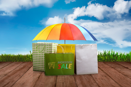 Colorful shopping bag and umbrella on wooden plank at Monsoon sale. Monsoon sale conceptの写真素材