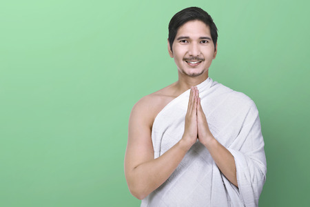 Handsome asian muslim with ihram clothes standing over green backgroundの写真素材