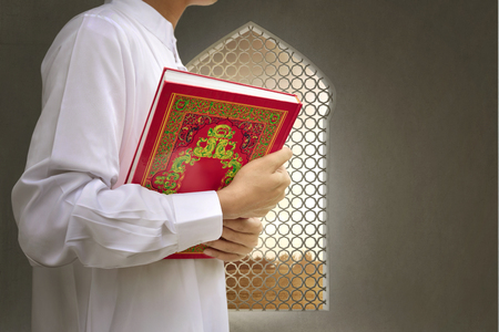 Muslim man bringing the Koran on his hand to the mosqueの写真素材