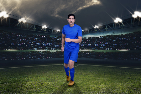 Handsome asian football player playing football on stadiumの写真素材