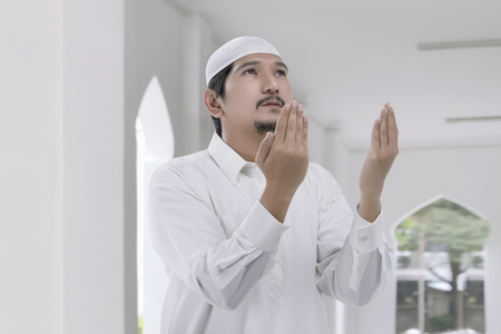 Religious asian muslim man with white cap praying on the mosqueの写真素材