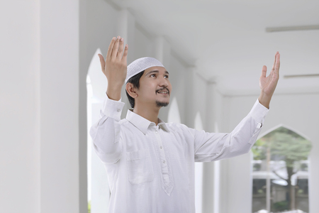 Smiling asian muslim man with traditional dress pray to god in the mosqueの写真素材