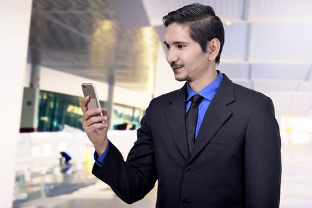 Young asian businessman with cellphone on his hand on the officeの写真素材