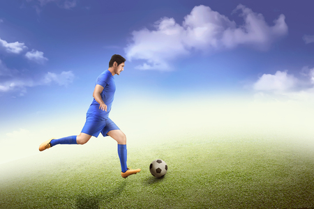 Side view of asian footballer kick the ball on the fieldの写真素材