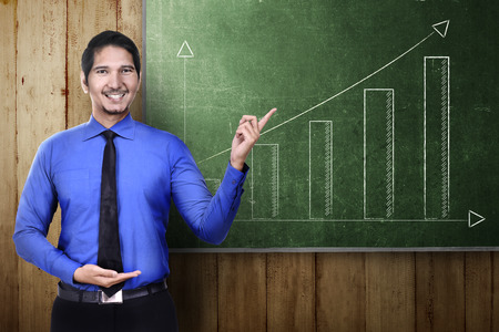 Successful asian businessman pointing a growth graph on the green boardの写真素材