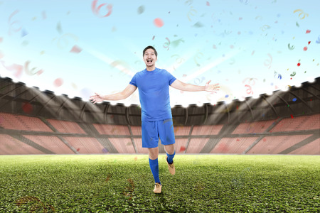 Young asian male football player celebrate victory on stadiumの写真素材