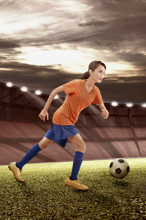 Professional asian female soccer player in action with the ball on the fieldの写真素材