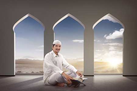 Religious asian muslim man with Koran sitting on the mosqueの写真素材