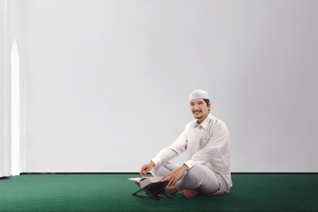 Smiling asian muslim man reading the Koran in the mosqueの写真素材