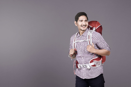 Happy asian backpacker ready to make a trip over colored backgroundの写真素材