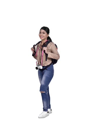 Portrait of asian traveler woman with camera and backpack standing isolated over white backgroundの写真素材