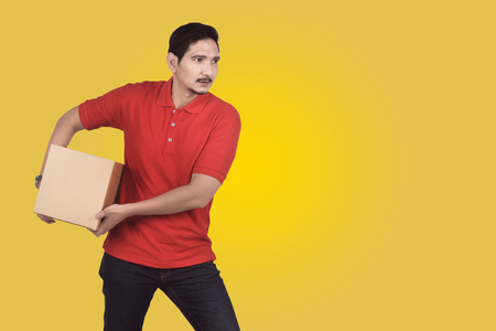 Attractive asian male delivery bring the parcel over colored backgroundの写真素材