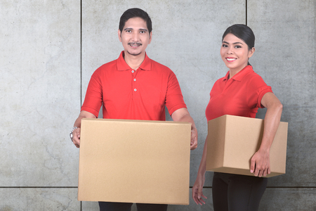 Young asian delivery service team with the parcel standing over wall backgroundの写真素材