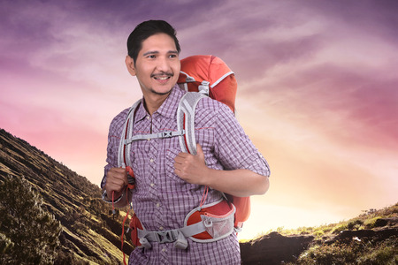 Happy asian tourist man with backpack climbing the mountainの写真素材