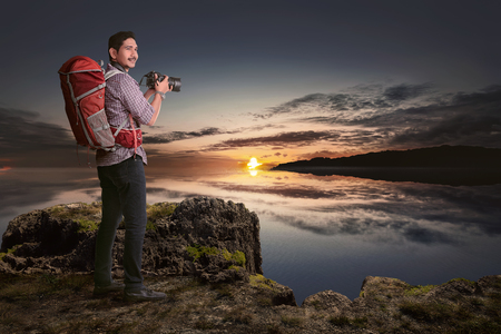 Attractive asian traveler man with camera want to taking a photos at sunsetの写真素材