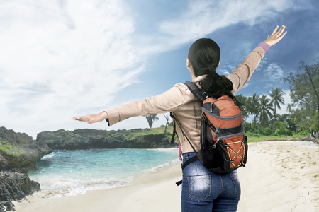 Rear view of asian traveler woman with backpack enjoying the view on the beachの写真素材