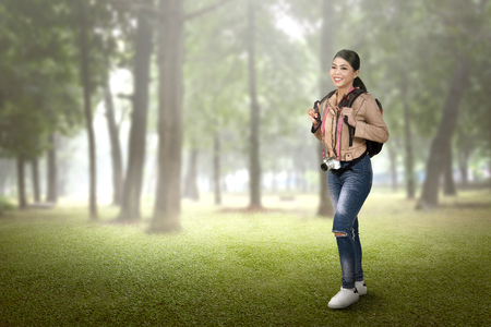 Pretty asian tourist woman with backpack and camera walking on the forest の写真素材