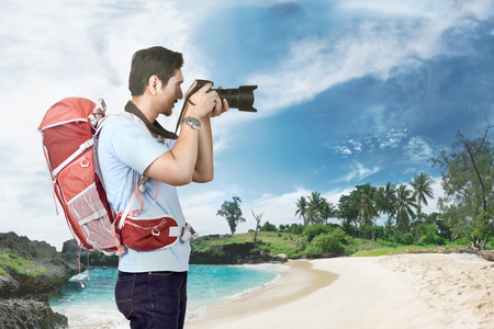 Attractive asian photographer man taking a photos on the beachの写真素材