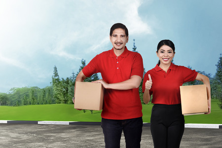 Smiling asian delivery service team with the package on the streetの写真素材