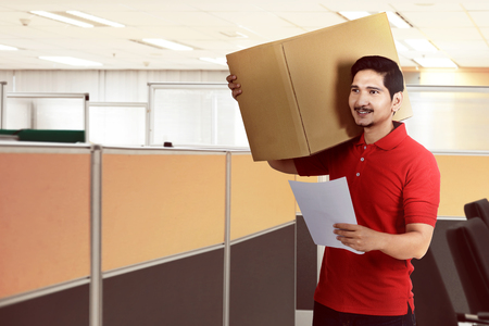 Handsome asian delivery man holding the package and sending to office buildingの写真素材