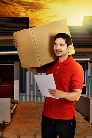 Professional asian male courier deliver the package to recipient houseの写真素材