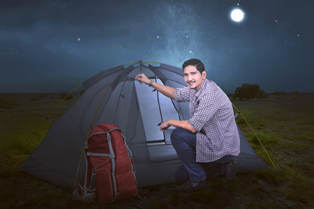 Young asian traveler man set up the tent for his rest at nightの写真素材