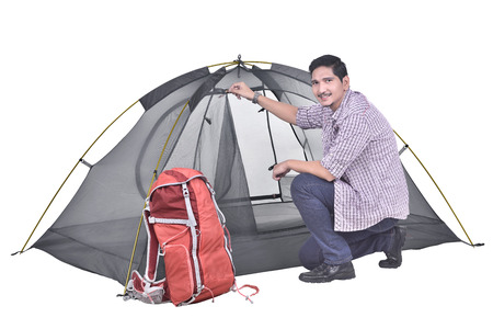 Portrait of asian backpacker man prepare the tent posing isolated over white backgroundの写真素材