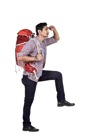 Side view of asian backpacker looking at view standing isolated over white backgroundの写真素材