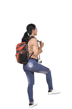 Rear view of asian traveler woman with backpack walking isolated over white backgroundの写真素材