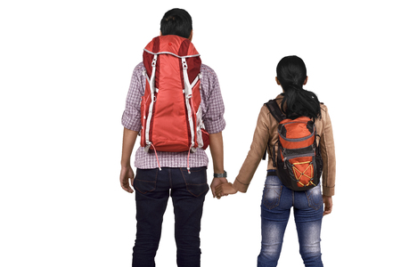 Rear view of asian couple with backpack holding hands posing isolated over white backgroundの写真素材