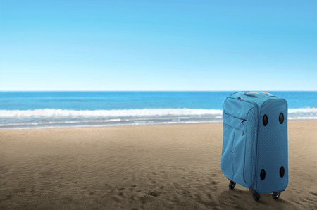 Blue suitcase on the beach. Summer travel conceptの写真素材