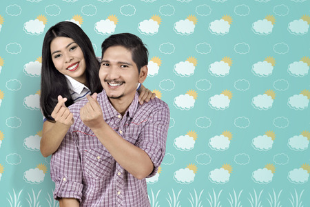 Romantic asian couple showing money sign over summer backgroundの写真素材