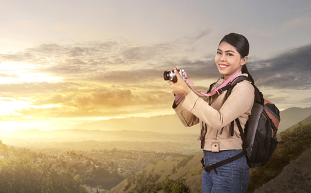 Beautiful asian photographer woman with camera and backpack at mountainの写真素材