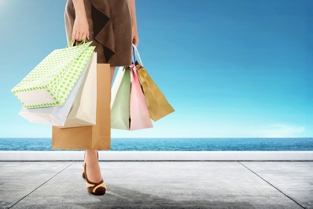 Woman carrying shopping bag walking with seascapes backgroundの写真素材