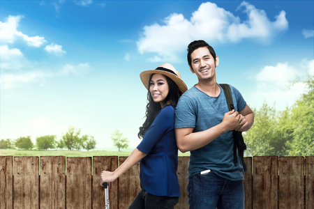 Happy asian traveler couple on the park with wooden fence on the backgroundの写真素材