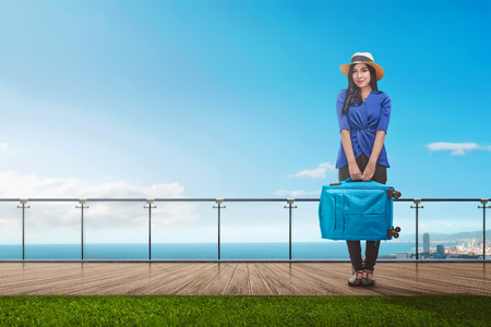 Pretty asian tourist woman with suitcase standing on balconyの写真素材