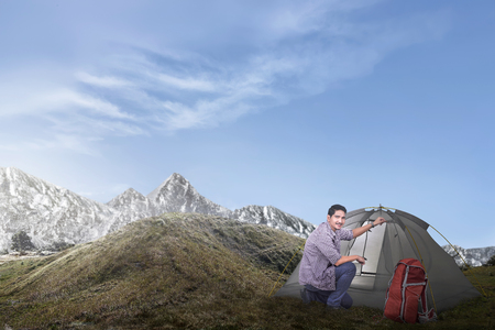 Young asian man set up a tent on the hillの写真素材