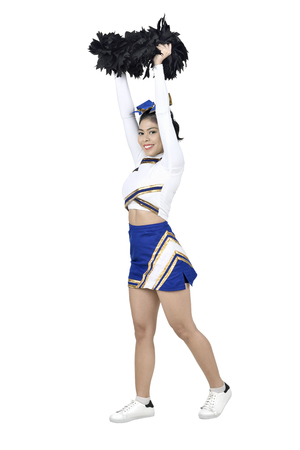 Happy asian cheerleader with pom poms in the air isolated over white backgroundの写真素材