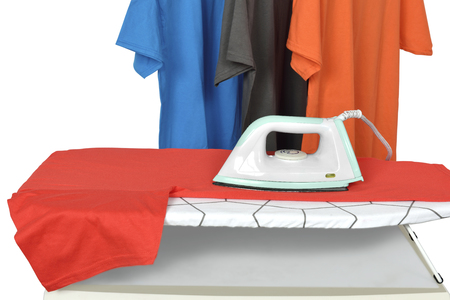 Clothes on ironing board with electric iron isolated over white backgroundの写真素材
