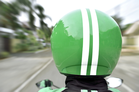 Rear view of motorcycle taxi ride with fast on the urban streetの写真素材