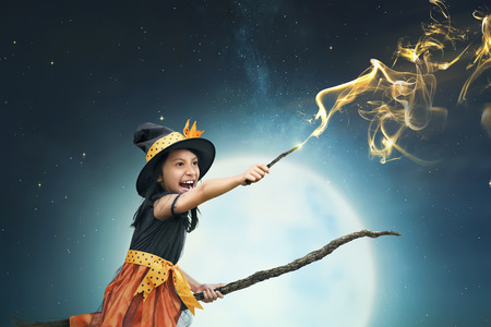 Beautiful asian witch girl using the magic wand with night backgroundの写真素材