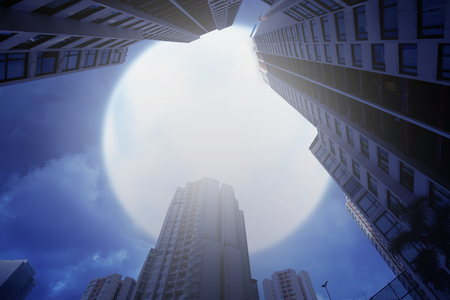 Skyscrapers building with dramatic full moon on the sky. Halloween backgroundの写真素材