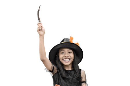 Happy asian little girl in witch costume holding a magic wand isolated over white backgroundの写真素材