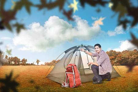 Young asian man set up a tent outdoors. Autumn recreationの写真素材