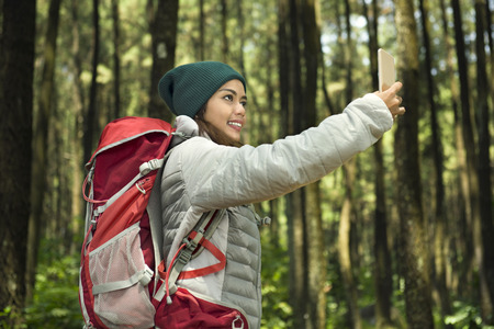 Beautiful asian tourist taking selfie with her phone on the forestの写真素材