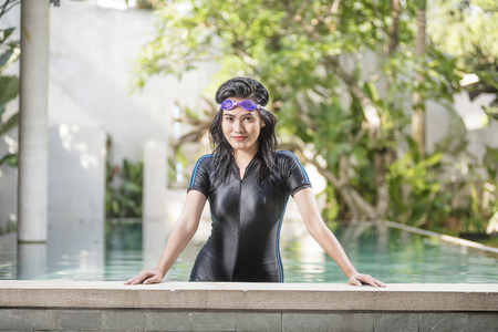 Happy asian woman with swimsuit posing on the poolsideの写真素材