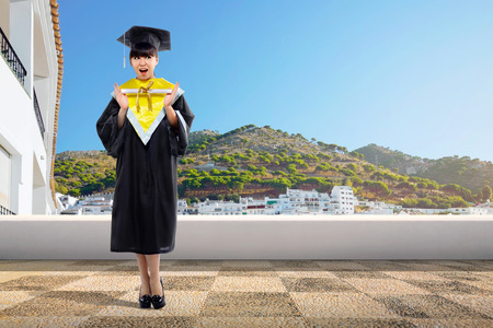 Happy asian student girl holding diploma scroll at graduation ceremonyの写真素材