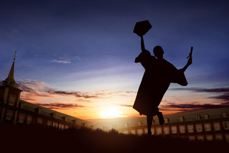 Silhouette of happy student woman celebrating graduation on campusの写真素材